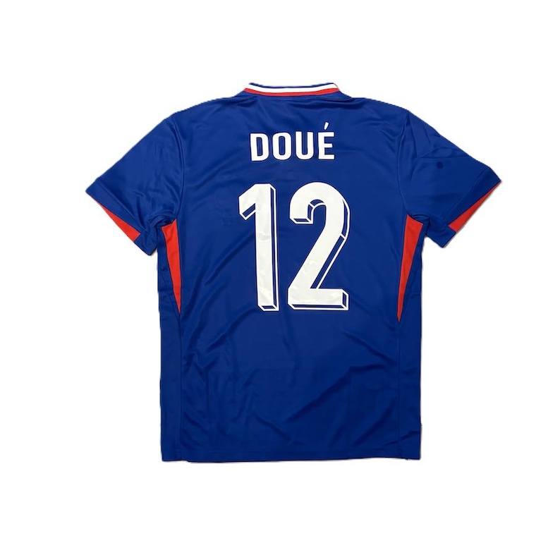 May include: A blue short-sleeved sports jersey featuring the name DOU&Eacute; and the number 12 printed in white on the back. The collar has red, white, and blue trim, and there are red accents on the sides of the garment under the sleeves.