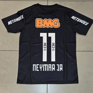 Pu&ograve; includere: Maglia nera con il numero 11 in bianco, il nome "NEYMAR JR" in bianco e il logo "CSU". La maglia presenta anche il logo "BMG" in arancione e bianco e il logo "NETSHOES" in bianco sulle maniche.