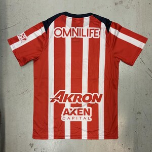 May include: Red and white striped jersey with the word "OMNILIFE" across the upper back. The jersey also features the words "AKRON", "AXEN", and "CAPITAL". The sleeves are red with white stripes.