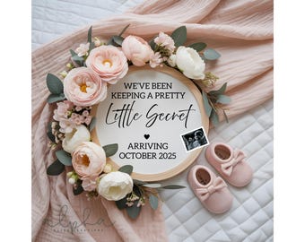 May include: A wooden announcement circle with the text "We've been keeping a pretty little secret" surrounded by pink and white flowers and greenery. Includes a sonogram photo and pink baby shoes.