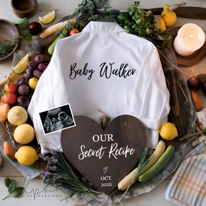 May include: A white shirt with "Baby Walker" written on it. A sonogram image and a wooden heart with "Our Secret Recipe" and "Oct. 2025" are also present. The image is surrounded by lemons, plums, and vegetables.