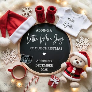 Op de afbeelding: Kerstmis-thema zwangerschapsaankondiging met een schoolbord met de tekst "Adding a Little More Joy to Our Christmas". Inclusief een kerstmuts, babyslofjes, een romper, een teddybeer en andere feestelijke items.