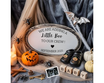 May include: An oval sign with the text WE ARE ADDING A Little Boo TO OUR CREW! SEPTEMBER 2025, featuring black baby shoes with pumpkin accents, a sonogram, wooden blocks spelling BABY, a carved orange pumpkin, small white pumpkins, and spiders.