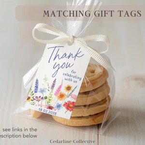 May include: A clear cellophane bag tied with a cream ribbon, containing a stack of cookies. A gift tag with the words "Thank you" and floral illustrations is attached. The tag also includes the date 19.02.2026.