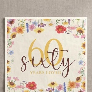 May include: Square paper napkins with floral border and the text "sixty years loved". The napkins are cream-colored with a floral design in red, yellow, and purple. The image also shows a stack of white napkins.