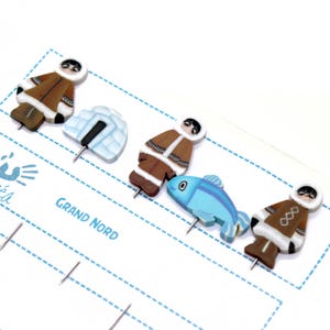 Könnte beinhalten: Satz mit fünf bunten Holzstiften, die ein Iglu, einen Fisch und drei Personen in traditioneller Kleidung zeigen. Die Stifte sind mit "Grand Nord" beschriftet und eignen sich perfekt, um Ihrem Pinnwand oder Ihrer Karte einen Hauch von Verspieltheit zu verleihen.