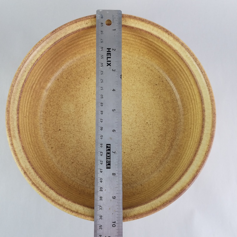 May include: A large, round, yellow ceramic bowl with a textured, rippled surface. The bowl is approximately 9 inches in diameter.