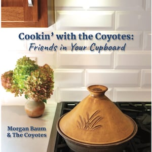 May include: A brown ceramic tagine with a design of grass on the lid. The tagine is sitting on a black stovetop. The text "Cookin' with the Coyotes: Friends in Your Cupboard" is above the tagine. The text "Morgan Baum & The Coyotes" is below the tagine.