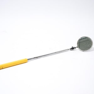 May include: A telescoping inspection mirror with a round mirror head and a yellow handle. The mirror is attached to a chrome-colored, extendable arm. The handle is approximately 4 inches long.