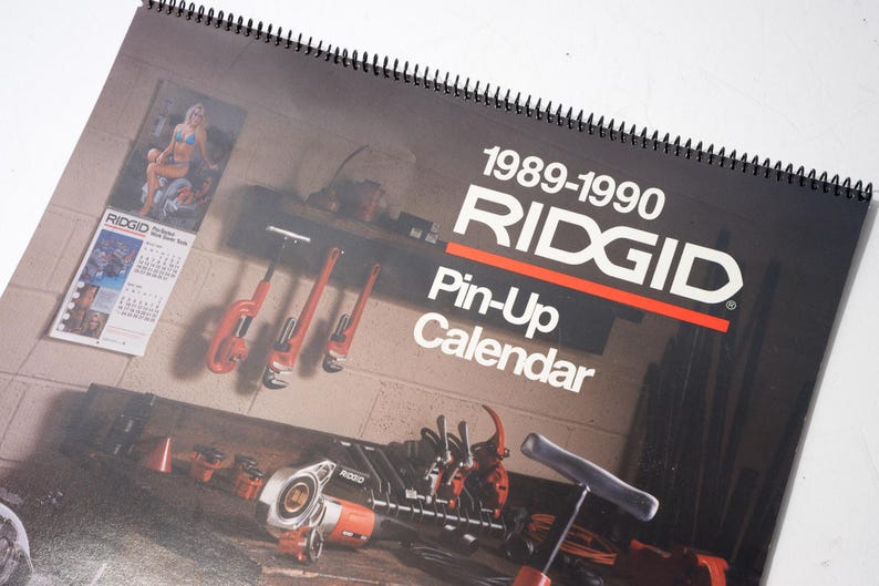 Peut inclure: Calendrier Ridgid Pin-Up de 1989-1990, avec une couverture noire et du texte blanc, ainsi qu'une bande rouge. Le calendrier pr&eacute;sente des images d'outils et une pin-up. Il est reli&eacute; en spirale.