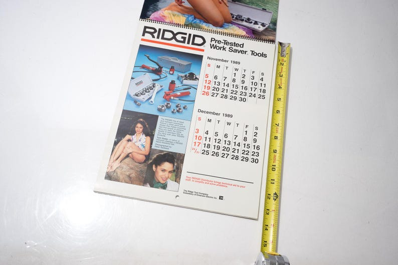 Peut inclure: Un calendrier RIDGID vintage de 1989, avec des images d'outils et de femmes. Le calendrier est ouvert sur novembre et d&eacute;cembre, avec un m&egrave;tre ruban jaune &agrave; c&ocirc;t&eacute;. Le calendrier mesure environ 25 cm de long.