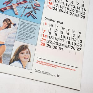 Peut inclure: Une page de calendrier vintage avec une femme en tenue de marin, et un calendrier pour octobre 1990. La page comprend &eacute;galement des images d'outils et du texte sur les outils RIDGID.
