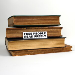 May include: A stack of three old, worn books with a white sticker on the second book that reads "FREE PEOPLE READ FREELY".