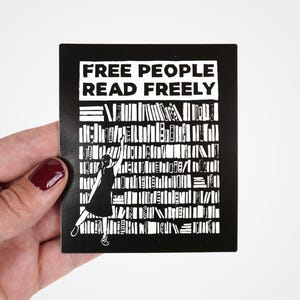 Puede incluir: Pegatina en blanco y negro con el texto "FREE PEOPLE READ FREELY" y la silueta de una persona que alcanza un libro en una estantería.