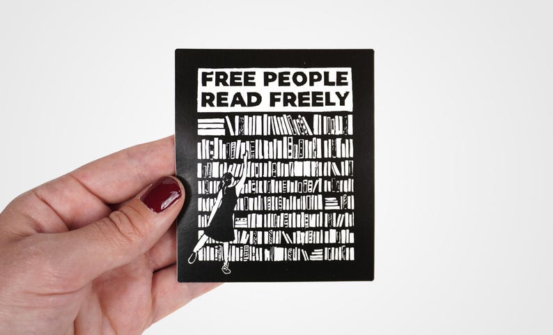 May include: Black and white sticker with the text "FREE PEOPLE READ FREELY" and a silhouette of a person reaching for a book on a bookshelf.