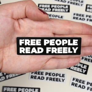 May include: A black sticker with white text that reads "FREE PEOPLE READ FREELY".