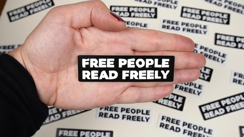 May include: A black sticker with white text that reads "FREE PEOPLE READ FREELY".