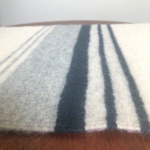 May include: A white and gray striped throw blanket with black stripes. The blanket is made of a soft, fuzzy material.