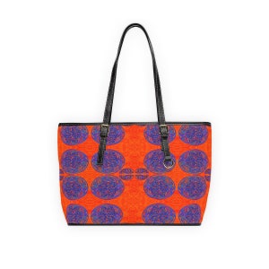 May include: A tote bag with black leather handles and a bright orange background with a repeating pattern of blue and purple circular designs.
