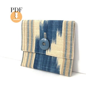 May include: A small blue and beige patterned fabric wallet with a single blue button closure.