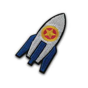 May include: An embroidered rocket patch in white and blue with a red and yellow star in the centre.