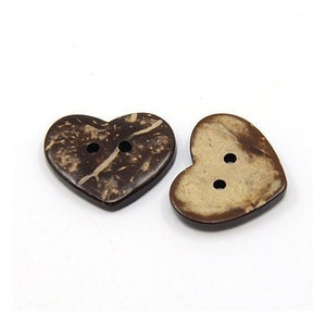 May include: Two heart-shaped buttons made from a dark brown material with visible grain. Each button has two holes for sewing. One button is a darker brown, the other a lighter tan colour.