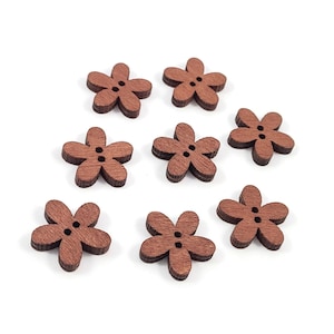 May include: A collection of eight wooden flower-shaped buttons. Each button is a warm brown color, featuring five petals and two small holes for sewing. The buttons are arranged on a white background.