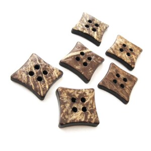 May include: Six brown and beige coconut shell buttons with four holes each. The buttons are shaped like diamonds and have a natural, rustic look.