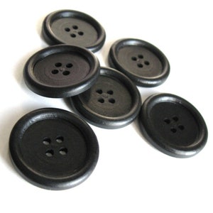 May include: Six black plastic buttons with four holes each. The buttons are arranged in a semi-circle pattern.
