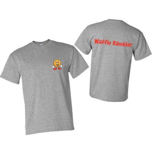 Puede incluir: Camiseta gris con un personaje de waffle sonriente en la parte delantera y el texto "Waffle Rambler" en la parte posterior.
