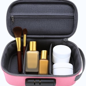 May include: A pink rectangular travel case with a black combination lock, featuring an open interior with a grey mesh zippered pocket, two makeup brushes with brown bristles, two rectangular glass bottles with gold caps, and two white jars.