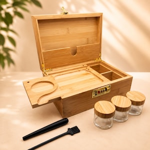May include: A light brown bamboo storage box with a combination lock, featuring an open lid, a sliding tray with a circular cutout, and internal compartments. Included are three small glass jars with bamboo lids, a black tool, and a black brush.