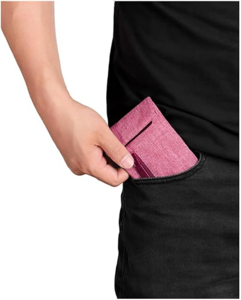 May include: A slim, rectangular wallet in a textured, dusty rose fabric. The wallet features a vertical slot on the front and a darker, solid-colored accent strip along the bottom edge, designed to fit compactly inside a pocket.