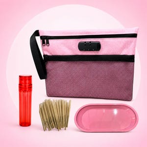 Puede incluir: Un estuche con cremallera rosa y negro con candado de combinación, un recipiente cilíndrico rojo translúcido, un grupo de conos de papel marrón claro y una bandeja ovalada rosa lisa. El estuche tiene un bolsillo frontal de malla negra y una correa.