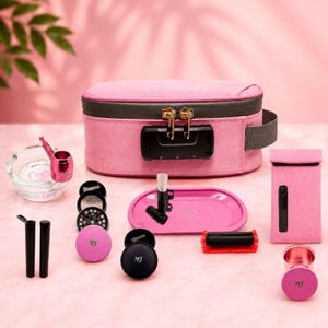 Könnte beinhalten: Eine rosa geruchsdichte Aufbewahrungstasche mit schwarzem Zahlenschloss, ein transparenter Glasaschenbecher, eine rosa Metallpfeife, ein rosa Drehtablett, ein rosa Beutel, eine schwarze Drehmaschine, zwei schwarze Röhrchen und zwei runde Grinder mit MTG-Aufdruck.