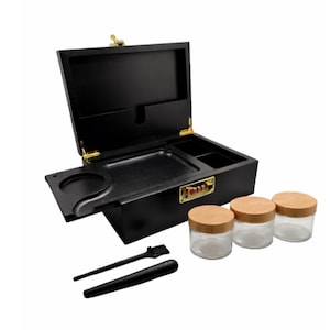 Puede incluir: Caja de madera negra con tapa con bisagras, bandeja incorporada y cerradura de combinación. Incluye tres frascos de vidrio con tapas de madera, un cepillo pequeño y una herramienta cilíndrica. La caja tiene herrajes dorados.