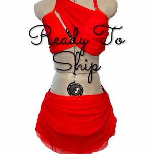 May include: A bright red two-piece outfit consisting of a halter-style top with a draped neckline and a matching skirt. The top features thin straps and a layered design. The text "Ready To Ship" is overlaid in black script across the center.