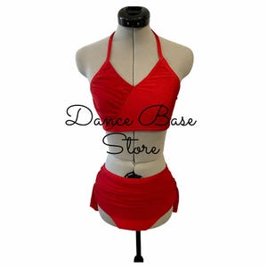 May include: A bright red two-piece dance outfit on a mannequin, featuring a halter-style crop top with a V-neckline and high-waisted bottoms with side ruching. The text Dance Base Store is overlaid in black script across the center of the garment.