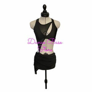 May include: A black dance outfit featuring a sleeveless top with sheer mesh panels, asymmetrical cutouts, and a ruched skirt. The text "Dance Base Store" is printed in pink across the center of the garment on a mannequin display.