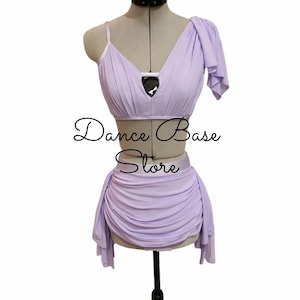 May include: A two-piece lavender dance outfit featuring a pleated crop top with a single shoulder drape and a matching ruched skirt. The top includes a central black triangular cutout detail. The text "Dance Base Store" is centered on the image.
