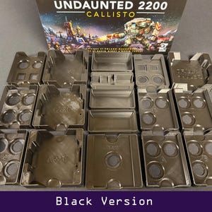 Peut inclure: Ensemble d'organisateurs de composants de jeu noirs, de formes et tailles vari&eacute;es, dispos&eacute;s en rang&eacute;es. La bo&icirc;te de jeu "Undaunted 2200 Callisto" est visible en arri&egrave;re-plan. Le texte "Black Version" est en bas.