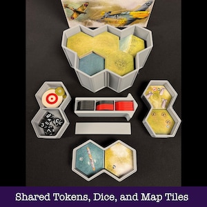 May include: A selection of grey game organisers containing dice, tokens, and map tiles. The set includes a target, dice, and hexagonal containers with yellow and blue game pieces. The image also shows a picture of airplanes.