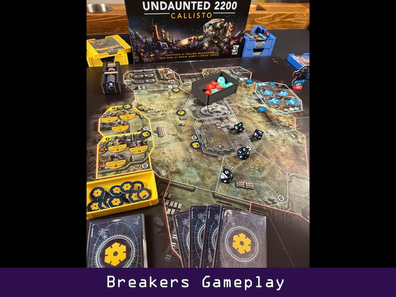 Peut inclure: Jeu de soci&eacute;t&eacute; "Undaunted 2200 Callisto" avec des pions, des d&eacute;s et des cartes. Le plateau de jeu est beige et gris avec un motif de carte. Les pi&egrave;ces du jeu sont dans des conteneurs jaunes et noirs. Le texte "Breakers Gameplay" est en bas.
