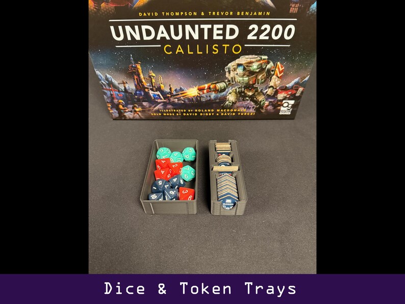Peut inclure: Bo&icirc;te de jeu de soci&eacute;t&eacute; "Undaunted 2200 Callisto" avec des d&eacute;s et des plateaux de jetons. Les plateaux gris contiennent des d&eacute;s rouges, bleus et verts, ainsi que des jetons de jeu. Le texte "Dice & Token Trays" est en bas.