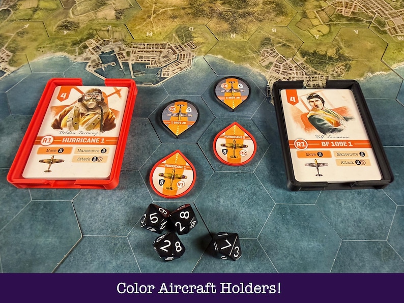 May include: A board game setup with aircraft cards in red and black holders, and circular and teardrop-shaped tokens. Black dice with white numbers are scattered around the game pieces. The text "Color Aircraft Holders!" is at the bottom.