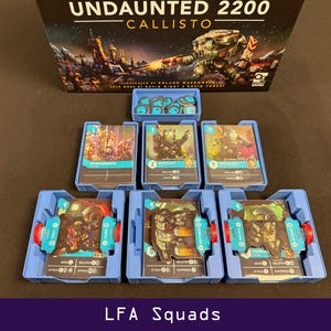 Peut inclure: Jeu de soci&eacute;t&eacute; "Undaunted 2200 Callisto" avec des &eacute;l&eacute;ments de jeu. L'image pr&eacute;sente des plateaux bleus contenant des cartes avec des illustrations de soldats et de v&eacute;hicules futuristes. Le texte "LFA Squads" est affich&eacute; en bas de l'image.
