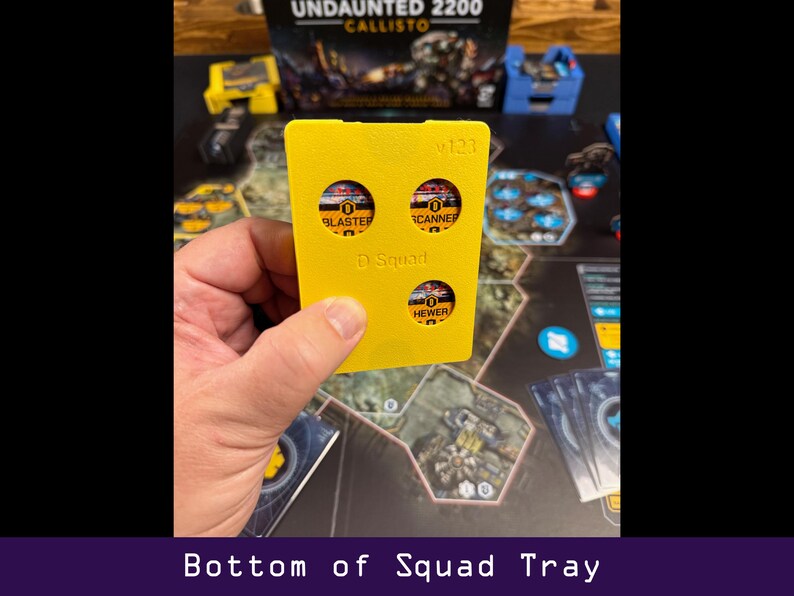Peut inclure: Un plateau de jeu jaune pour le jeu de soci&eacute;t&eacute; Undaunted 2200: Callisto, avec trois d&eacute;coupes circulaires &eacute;tiquet&eacute;es "Blaster", "Scanner" et "Hewer". Le plateau est &eacute;tiquet&eacute; "D Squad" et "v123". Le texte "Bottom of Squad Tray" est en bas.