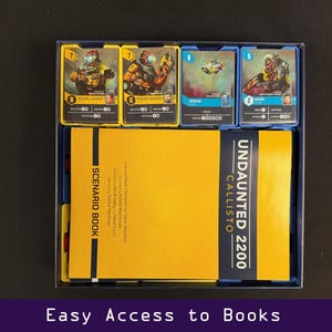 Peut inclure: Une bo&icirc;te de jeu de soci&eacute;t&eacute; avec des composants jaunes et bleus. La bo&icirc;te contient des livrets de sc&eacute;narios et des cartes avec des illustrations de personnages et de v&eacute;hicules. Le texte "UNDAUNTED 2200 CALLISTO" est visible sur le livre. Le texte "Easy Access to Books" est en bas.