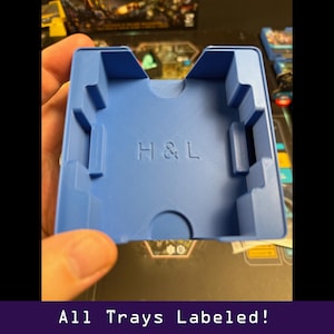 Peut inclure: Un plateau de jeu en plastique bleu avec les lettres en relief "H & L". Le plateau est de forme rectangulaire avec plusieurs compartiments et d&eacute;coupes. Le texte "All Trays Labeled!" est au bas de l'image.
