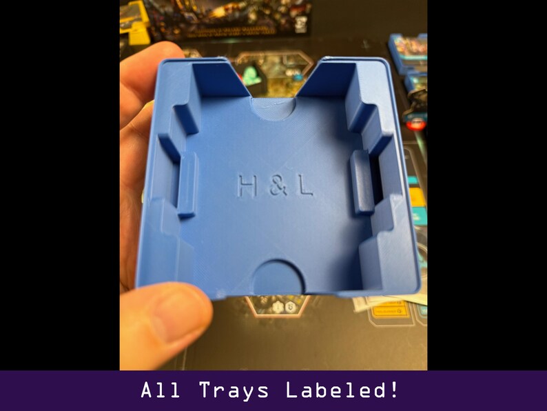 Peut inclure: Un plateau de jeu en plastique bleu avec les lettres en relief "H & L". Le plateau est de forme rectangulaire avec plusieurs compartiments et d&eacute;coupes. Le texte "All Trays Labeled!" est au bas de l'image.
